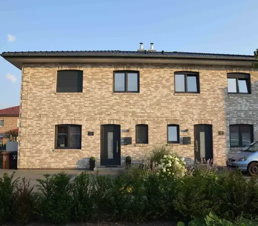 Modernes Doppelhaus aus Klinkerstein mit Garten und Einfahrt in ruhiger Wohnsiedlung.